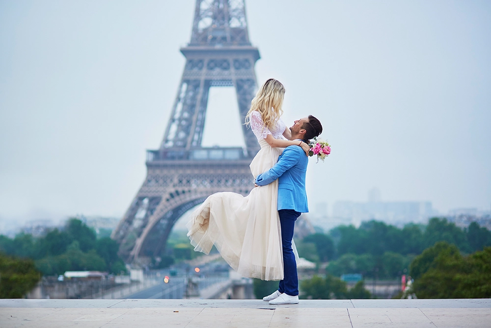 Casal celebrando viagem romântica em Paris diante da Torre Eiffel